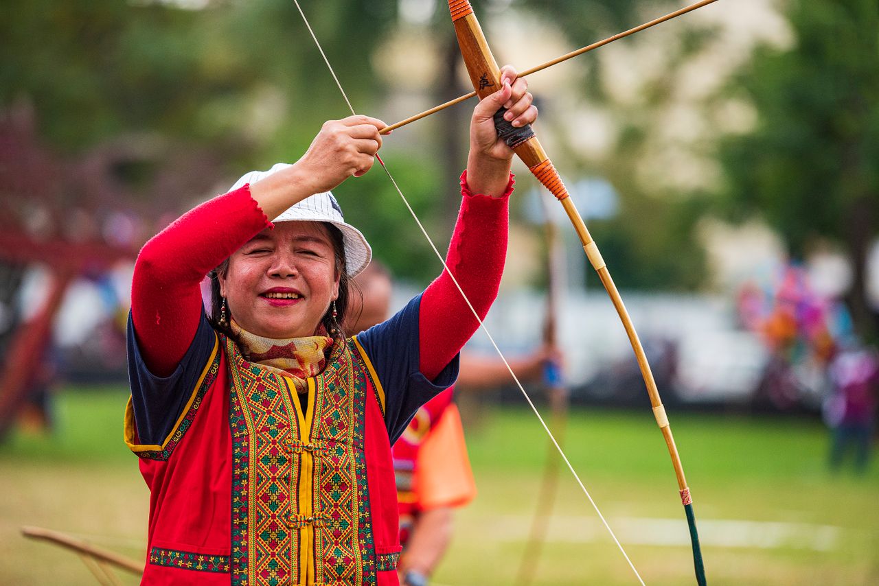 services-01 Asian woman skillfully aiming and enjoying traditional archery outdoors in Taiwan.
