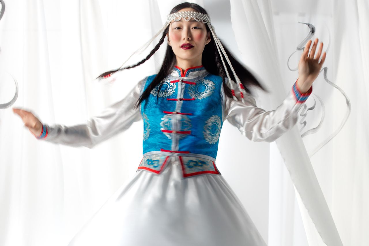 about-01 Energetic Asian woman in traditional Mongolian clothing captured in motion.